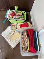 Overall view of fabric baskets and plastic bin containing folded linens, napkins, placemats, and tea towels.