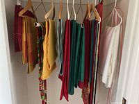 Assorted table linens hanging on wooden hangers showing various fabric placemats, table runners, and white linen
