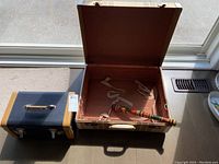 Two bags open and closed showing contents inside large suitcase and overall exterior of smaller bag and suitcase.