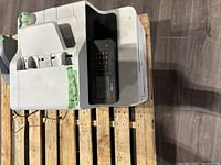 Photo showing white Brother multifunction printer on wooden pallet with keypad and multiple paper trays