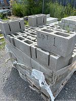 Stack of gray concrete cinder blocks on wooden pallet outdoors