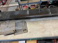 Metal door threshold and several wrapped metal plates and brackets on a shelf.