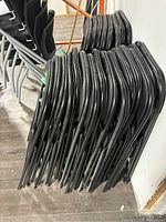 Two stacks of black folding chairs showing the side profile of frames and thickness of chairs