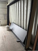 Disassembled door frame and panels leaning against container wall