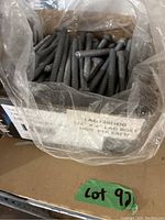 Open box showing numerous hex lag bolts inside, coated in dark gray metal finish.