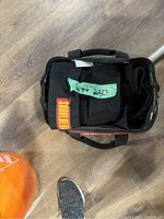 Photo of two large black padded shoulder straps inside a black carrying bag on wooden floor.