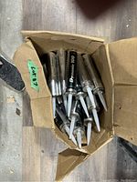 Box containing about 20 new Dymonic 100 tubes with white dispensing nozzles.