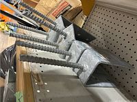 Photo showing multiple galvanized post brackets with attached rebar rods.