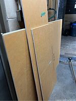 Several Schleuter boards of different sizes leaning against a wall in a workshop or garage setting. Boards have grid patterns and are flat panels.