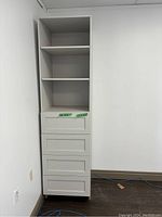 Full view of white tall cabinet showing three open shelves and three recessed-panel drawers