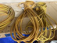 Various coiled yellow and orange electrical extension cords on wood shelf