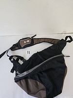 Front view of the black and tan Eureka courier backpack showing multiple zippered compartments and adjustable strap.