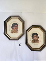 Two framed cross stitch pictures of Indigenous children side by side on white background
