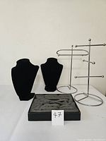 Photo showing 2 black velvet jewelry busts, 2 chrome multi-arm jewelry stands, and 1 black ring display box with multiple slots.
