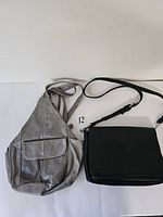 Photo shows two bags on a white surface, the light grey leather backpack with a flap pocket on front and the black CoLab purse with a crossbody strap
