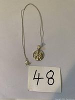 Silver Madonna and Child pendant necklace laid out on plain white background with number card.
