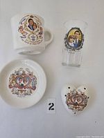 Front view of four vintage Prince Charles and Lady Di commemorative items: mug, glass, plate, heart-shaped salt and pepper shakers.