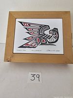 Front view of wood box with inset tile showing Indigenous bird design and signature