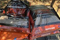 Three full bags and one open partially full bag of Traeger Signature hardwood pellets made from maple and cherry wood.