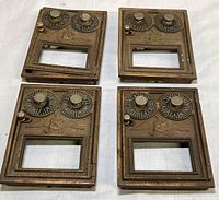 Four vintage Corbin postal box doors with eagle emblem and double dials shown from front on white surface.