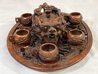 Full view of dragon-themed teapot, four cups, and carved platter showing design and overall condition