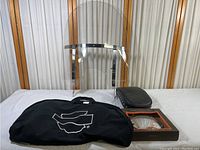 Photo shows the entire lot with all items together: transparent motorcycle windscreen with metal brackets standing upright behind a black motorcycle seat and a black Harley Davidson branded garment bag.