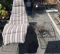 Two Mid-Century Modern Homecrest wire banana chairs, one with a striped gray and white cushion, placed outdoors. Visible light rust on metal frames.