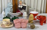 Porcelain and ceramic collection displayed including figurines, small dishes, salt and pepper shakers, decorative shoes, and teacup.