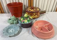 Overview photo showing all six ceramic and pottery items arranged on table including red flower pot, decorative handled pot, fruit-topped basket container, cat planter, rabbit plate, and segmented dish.
