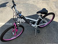 Full view of Schwinn Cascade bike showing white steel frame with pink rims and knobby tires, front suspension fork, padded black seat and handlebars with shifters.