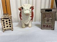 Front view of three vintage metal coin banks: cow, stove, U.S. mailbox