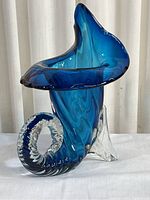 Full view of blue Murano glass cornucopia vase with flared top and curved base.