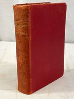Front and spine view of the antique Shakespeare book with red cloth cover and worn brown leather spine.