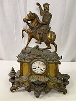 Front view of tall antique metal figural mantle clock with rider on horse, showing wear and detailed sculpting.