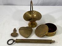 Overview of brass objects including the scale, basket, lidded boxes, and canister