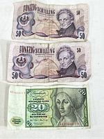 Front side of two Austria 50 Schilling 1970 banknotes and front of one Germany 20 Deutsche Mark 1970 note, showing portraits and denomination markings.