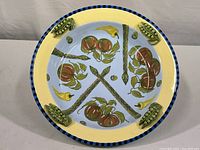 Top view showing the hand-painted vegetables and sculpted pea pods on the rim.