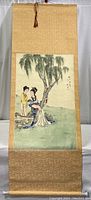 Full view of the large Japanese hanging scroll depicting two women under a tree beside water, mounted on golden silk fabric.