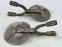 Full view of both vintage South American Gaucho spurs showing large round multi-spiked rowels and arm design