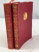 Two hardcover books with red leather covers and gold embossed spines.