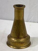 Side view of the vintage brass fire hose nozzle showing its tapered conical shape and visible surface marks.