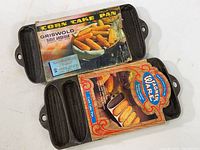 Both cast iron corn stick pans shown with their original cardboard sleeves, confirming brand and style.
