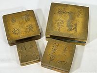 Top-down photo of all four brass ink boxes grouped together showing engraved Chinese calligraphy on all lids.