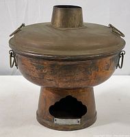 Front view of large vintage copper hot pot showing scalloped cutout on base for charcoal and side ring handles.