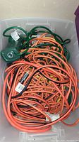 Bin filled with tangled orange extension cords and a green power strip at the back.