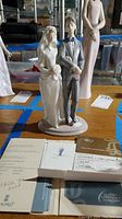 Photo showing full view of the bride and groom porcelain figurine along with several accompanying Lladro documents and authenticity certificate.