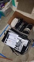 Photo showing Epson Perfection scanner(s) and multiple business telephones packed in a box. Items include various cords and adapters.