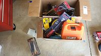 Photo showing two boxes filled with assorted hand and car tools, including multiple saw blade packages mainly from DeWalt, a black and orange tool handle, and other items.