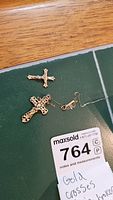 Both pendants and broken chain laid out on dark green surface next to MaxSold lot card