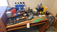 Wide view of office supplies arrayed on desk including label maker, duster sprays, adhesives, scissors, and paper clips